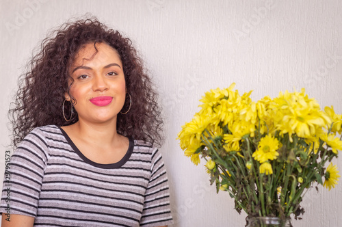 Young woman with curly hair and red lips with yellow flowers