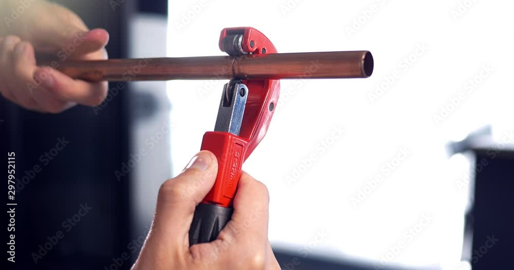 4K Plumber hand cutting Copper Metal Pipe. Man using cutter tool