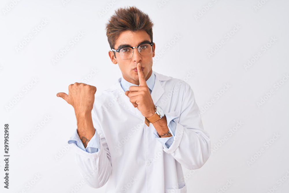 Young handsome sciencist man wearing glasses and coat over isolated white background asking to be quiet with finger on lips pointing with hand to the side. Silence and secret concept. Young handsome sciencist man wearing glasses and coat over isolated white background asking to be quiet with finger on lips pointing with hand to the side. Silence and secret concept.
