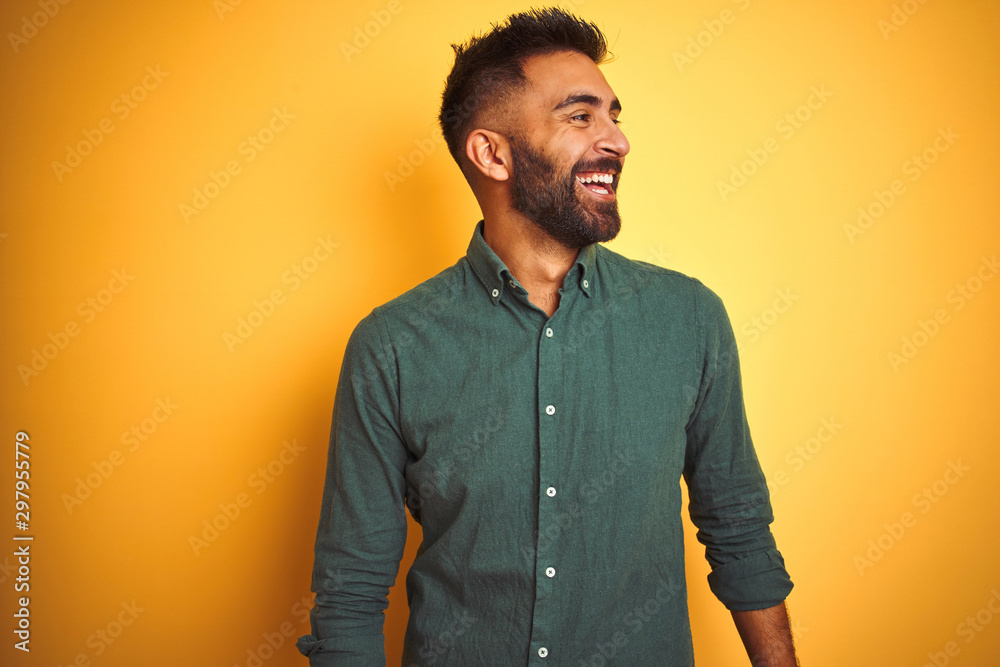 Fototapeta premium Young indian businessman wearing elegant shirt standing over isolated white background looking away to side with smile on face, natural expression. Laughing confident.