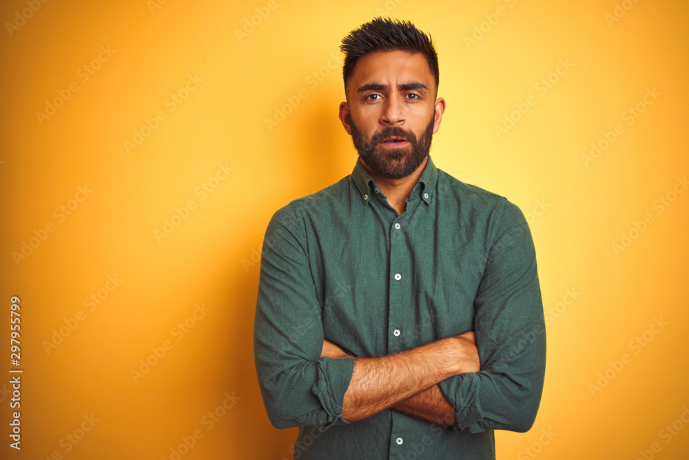 Fototapeta premium Young indian businessman wearing elegant shirt standing over isolated white background skeptic and nervous, disapproving expression on face with crossed arms. Negative person.