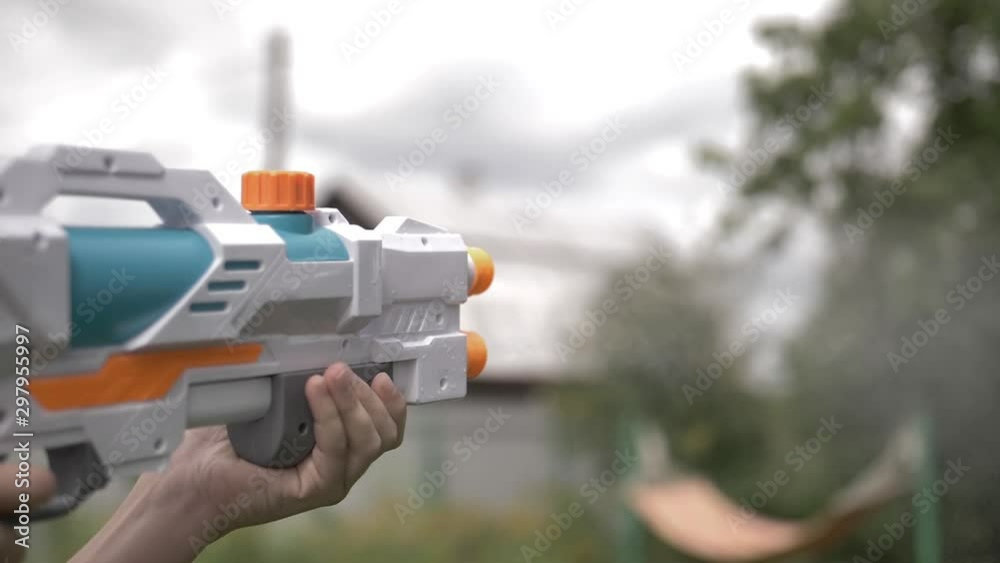 happy boy shoots a water pistol outdoors, have fun happy boy shoots a water pistol outdoors, have fun
