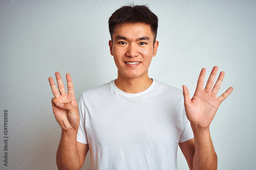 Young asian chinese man wearing t-shirt standing over isolated white background showing and pointing up with fingers number eight while smiling confident and happy. Young asian chinese man wearing t-shirt standing over isolated white background showing and pointing up with fingers number eight while smiling confident and happy.