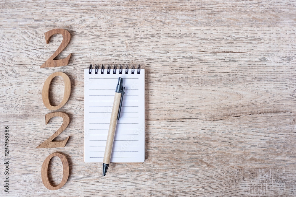 2020 Happy New years with paper notebook, pen and wooden number on table for copy space. New Start, Resolution, Goals and Mission Concept 2020 Happy New years with paper notebook, pen and wooden number on table for copy space. New Start, Resolution, Goals and Mission Concept