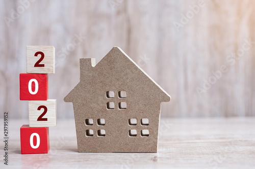 2020 Happy New Year with house model on wooden background. Banking, real estate, investment, financial, savings and New Year Resolution concepts