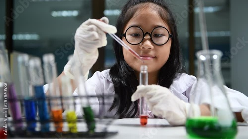 Cute little girl wearing lab coat making experiment in chemical laboratory, ecucation and science concept photo