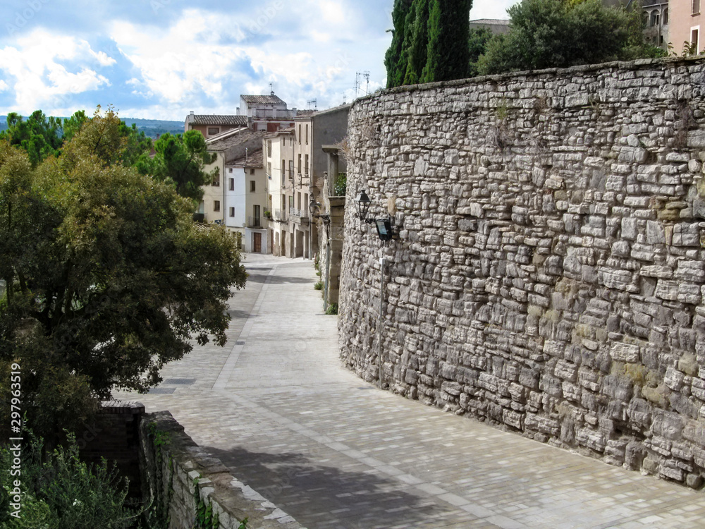 Provincial street with stone walls of buildings in the ancient Spanish village of Cervera (Lleida, Catalonia). Beautiful rural summer landscape, surfaces with copy space