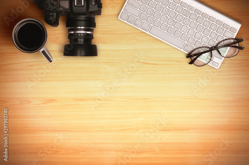 Wood office desk table with laptop, eyeglass, coffee cup and photography device, top view flat layout concept. Image blank for copy space.