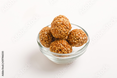 Indian sweet Sesame seeds ball or called in Hindi til ke laddu in glass bowl on white background 