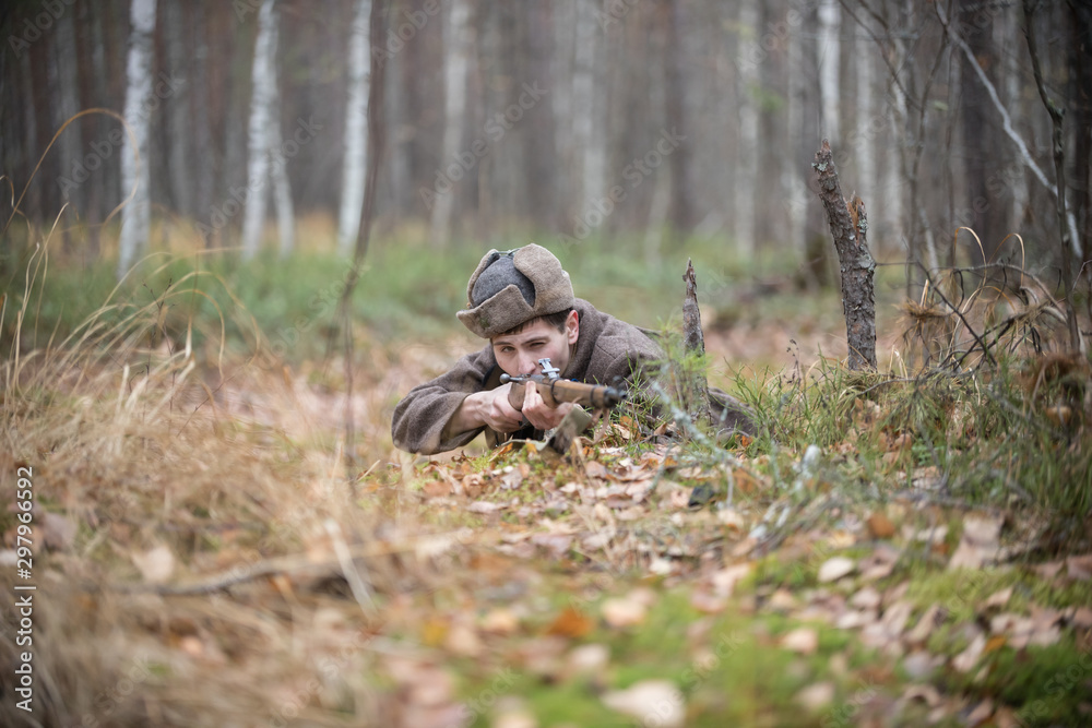 A soldier of World War II is lying in the forest and is going to shoot A soldier of World War II is lying in the forest and is going to shoot