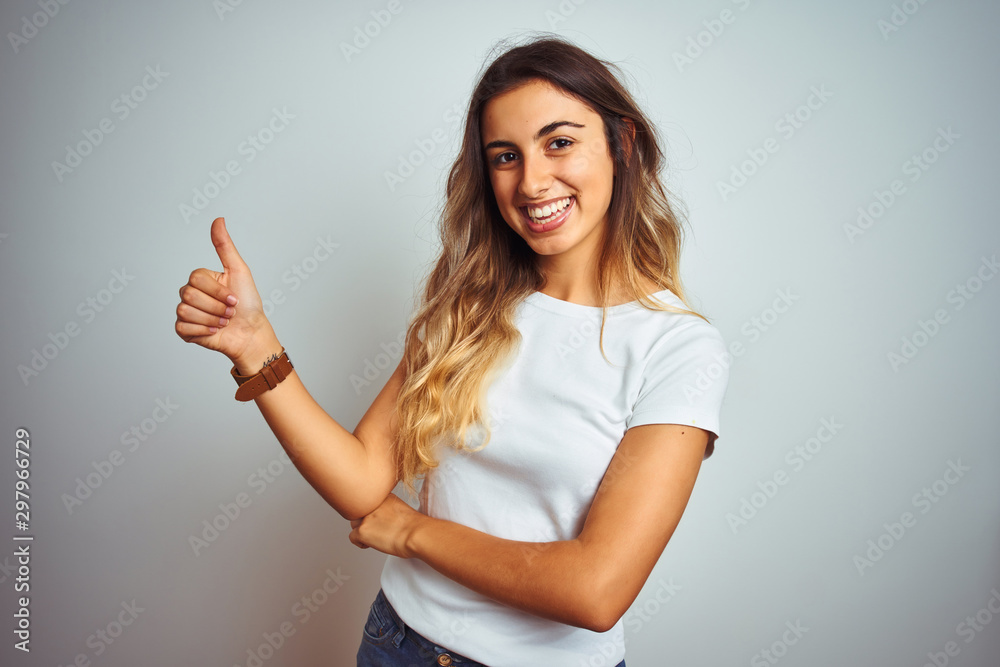 Young beautiful woman wearing casual white t-shirt over isolated background Looking proud, smiling doing thumbs up gesture to the side Young beautiful woman wearing casual white t-shirt over isolated background Looking proud, smiling doing thumbs up gesture to the side