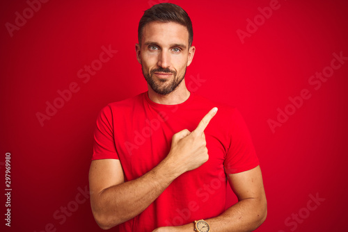 Young handsome man wearing casual t-shirt over red isolated background Pointing with hand finger to the side showing advertisement, serious and calm face