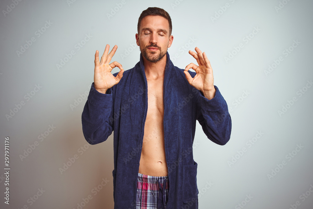 Fototapeta premium Sexy shirtless man wearing comfortable pajamas and robe over isolated background relax and smiling with eyes closed doing meditation gesture with fingers. Yoga concept.
