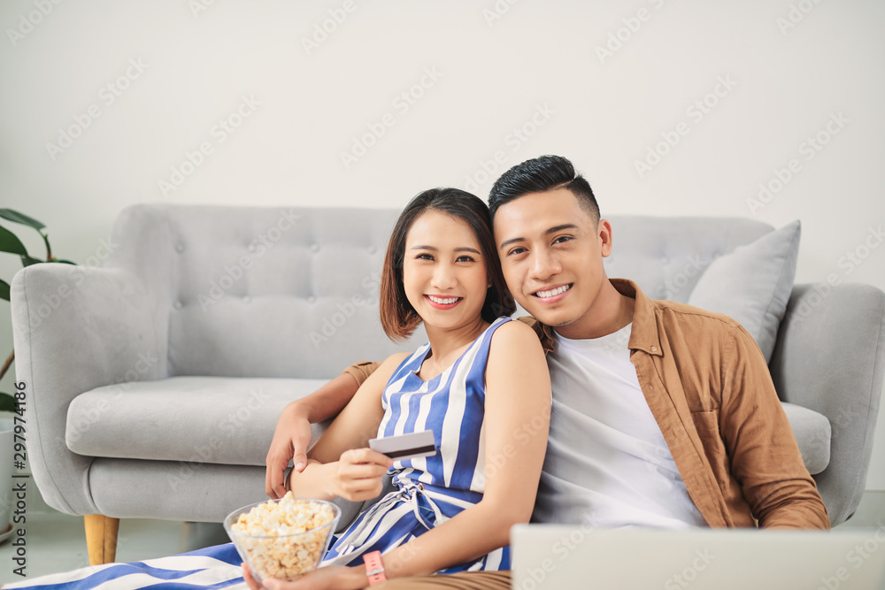 Φωτογραφία Young Asian couple loking at laptop screen to buy online or watching movie at ho