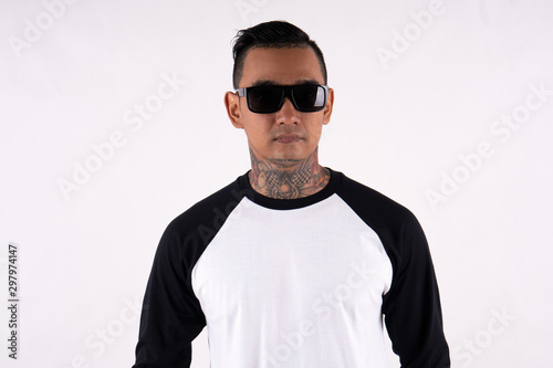 Young man wearing blank plain t shirt isolated on white background. Young hipster man wearing raglan 3/4 sleeve and sunglasses while posing. Ready for your mockup design © DendraCreative