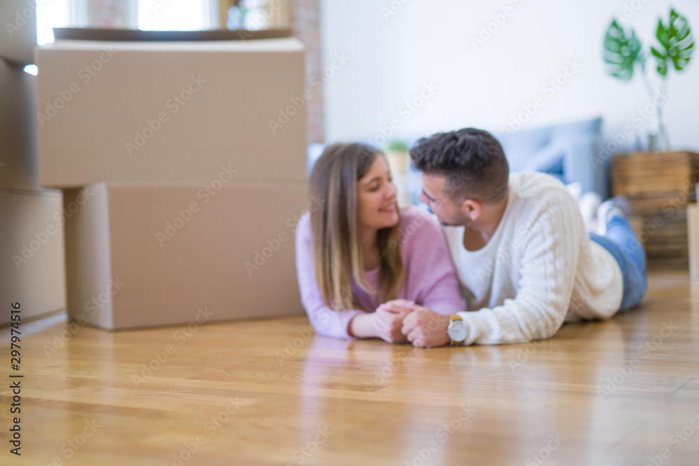 Young beautiful couple in love moving to new home, lying on the floor around cardboard boxes, very happy and cheerful for new apartment Young beautiful couple in love moving to new home, lying on the floor around cardboard boxes, very happy and cheerful for new apartment