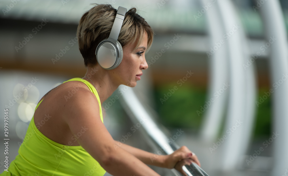 Young sport woman with earphones listening to music for relax after hard workout exercise