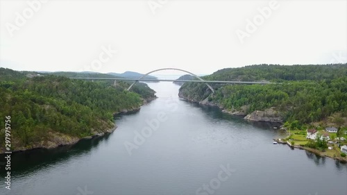 Modern arched bridge across narrow inlet in Scandinavia, construction engineering and transportation concept, aerial push in view of Svinesund bridge photo