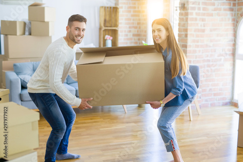 Beautiful young couple moving to a new home, holding big cardboard box © Krakenimages.com
