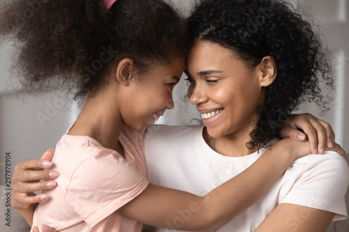 Bild auf Leinwand Smiling black mother and daughter look in eyes hugging