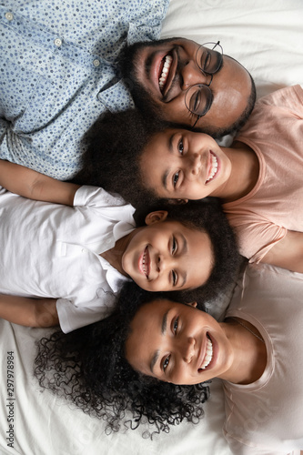 Top view portrait of smiling black family lying on bed