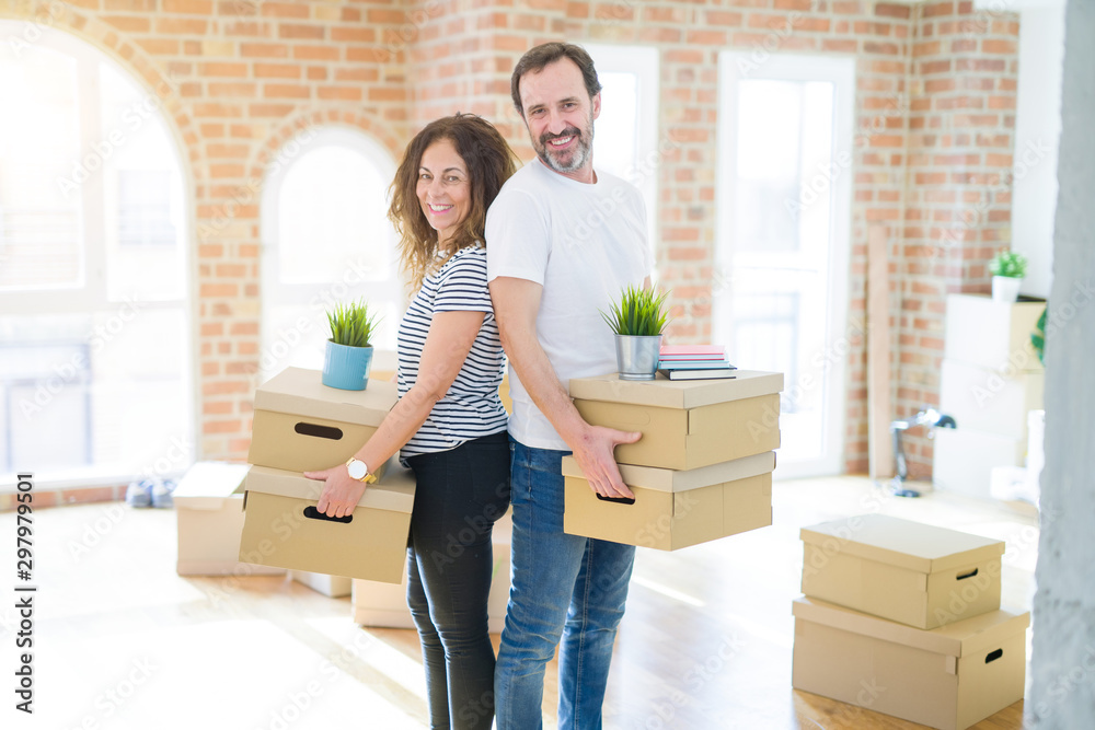 Middle age senior couple moving to a new house, holding cardboard boxing smiling happy in love with apartmant Middle age senior couple moving to a new house, holding cardboard boxing smiling happy in love with apartmant