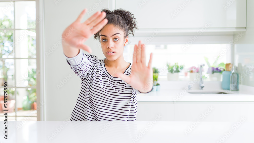 Beautiful african american woman with afro hair wearing casual striped sweater doing frame using hands palms and fingers, camera perspective Beautiful african american woman with afro hair wearing casual striped sweater doing frame using hands palms and fingers, camera perspective