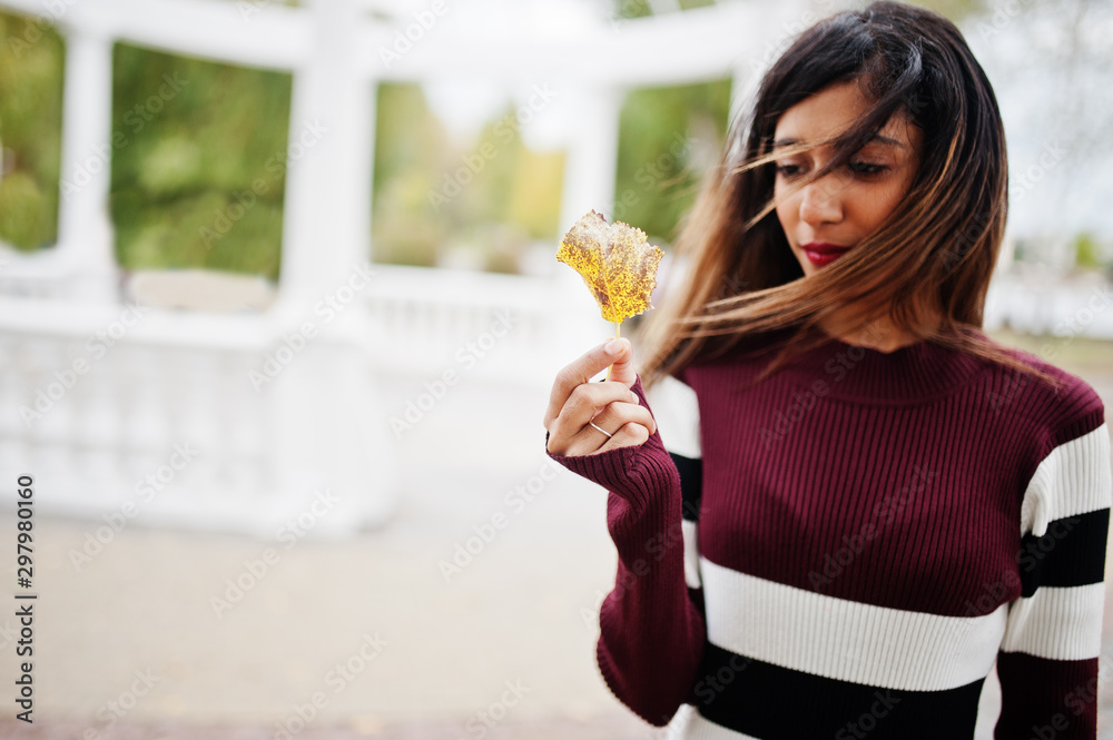 Portrait of young beautiful indian or south asian teenage girl in dress hold yellow leaves at hand.