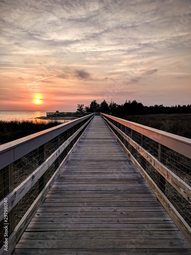Fototapeta Naklejka Na Ścianę i Meble -  Cloudy sunset by boardwalk and water