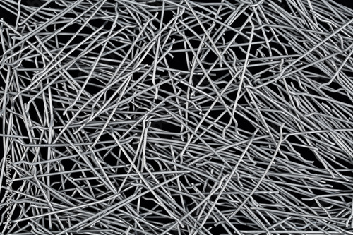 Close up, top down view of hooked end steel fibers for concrete structural reinforcement on black background