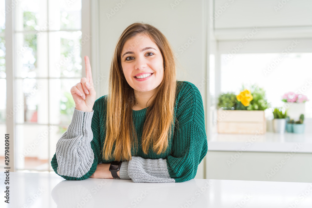 Young beautiful plus size woman wearing casual striped sweater showing and pointing up with finger number one while smiling confident and happy. Young beautiful plus size woman wearing casual striped sweater showing and pointing up with finger number one while smiling confident and happy.