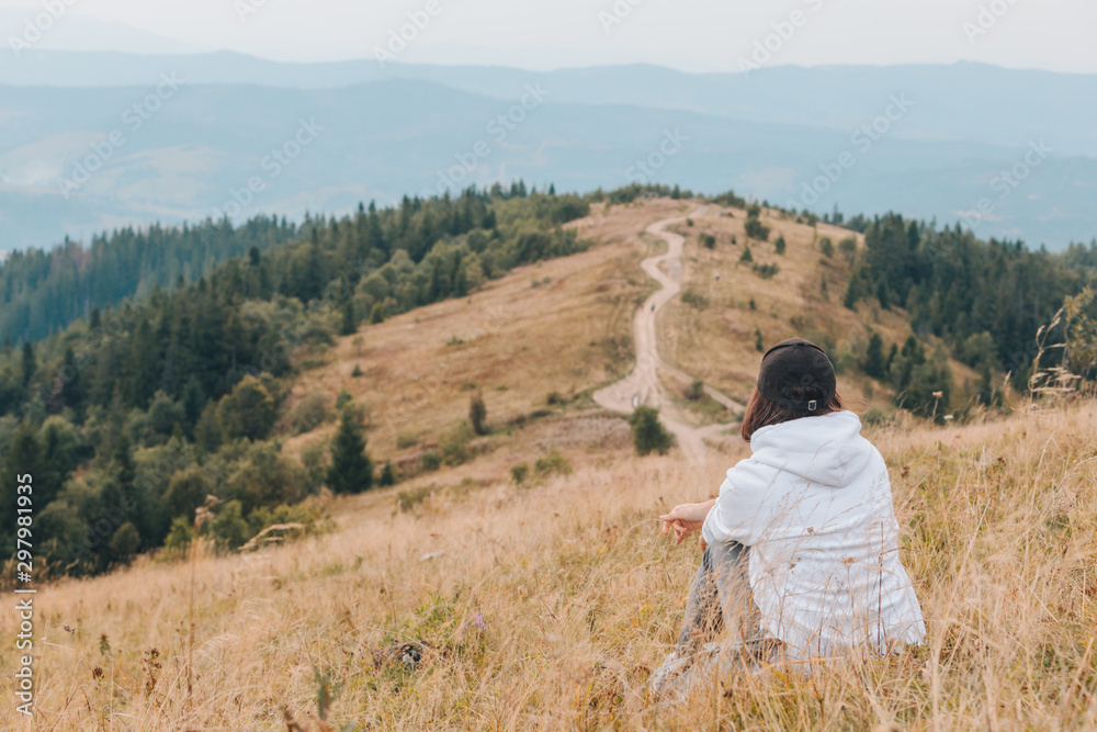 woman sitting on the ground looking at mountains hiking concept