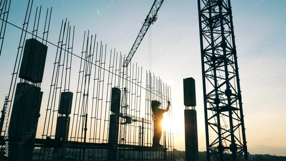 Construction site with cranes and the engineer working with metal