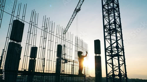 Construction site with cranes and the engineer working with metal
