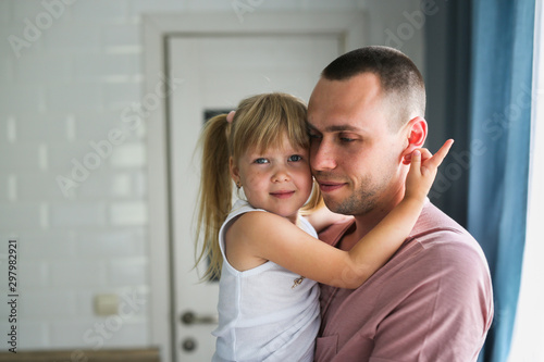 Blonde daughter hugs dad tightly at home in room