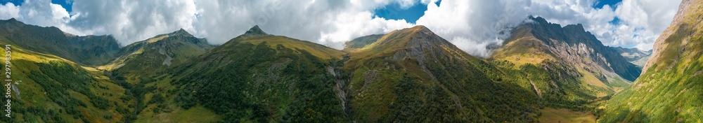Ultra wide panorama of mountain landscape in autumn; mountain ranges, valleys, river canyons and alpine meadows; dramatic clouds on peaks, blue sunny sky; natural outdoor travel background, Caucasus Ultra wide panorama of mountain landscape in autumn; mountain ranges, valleys, river canyons and alpine meadows; dramatic clouds on peaks, blue sunny sky; natural outdoor travel background, Caucasus
