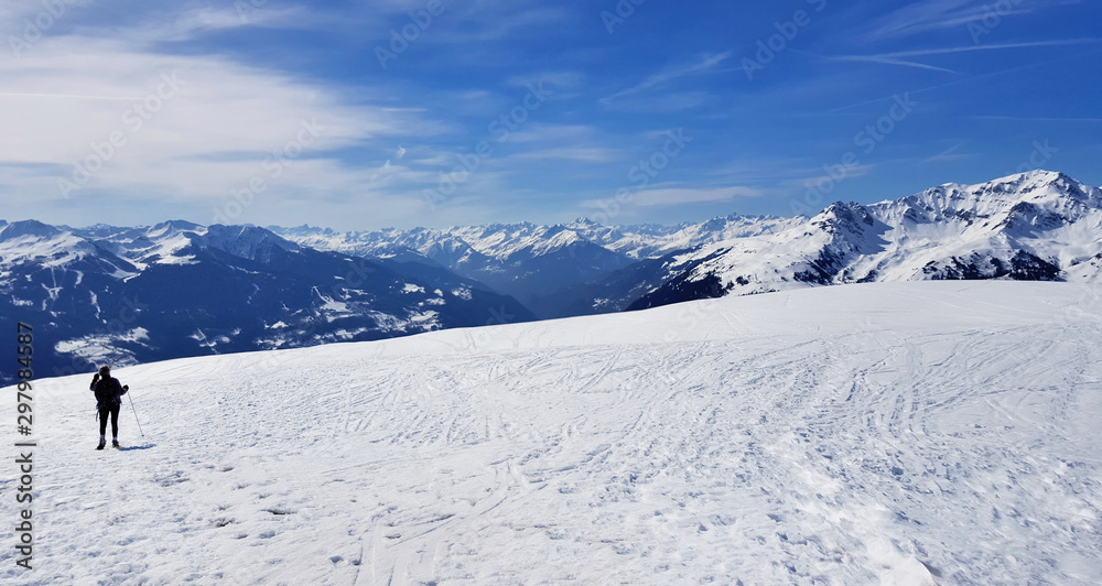 little  silhouette of a hiker in snowy mountain under blue sky