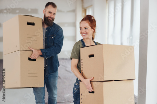 Happy young couple carrying boxes into a new home