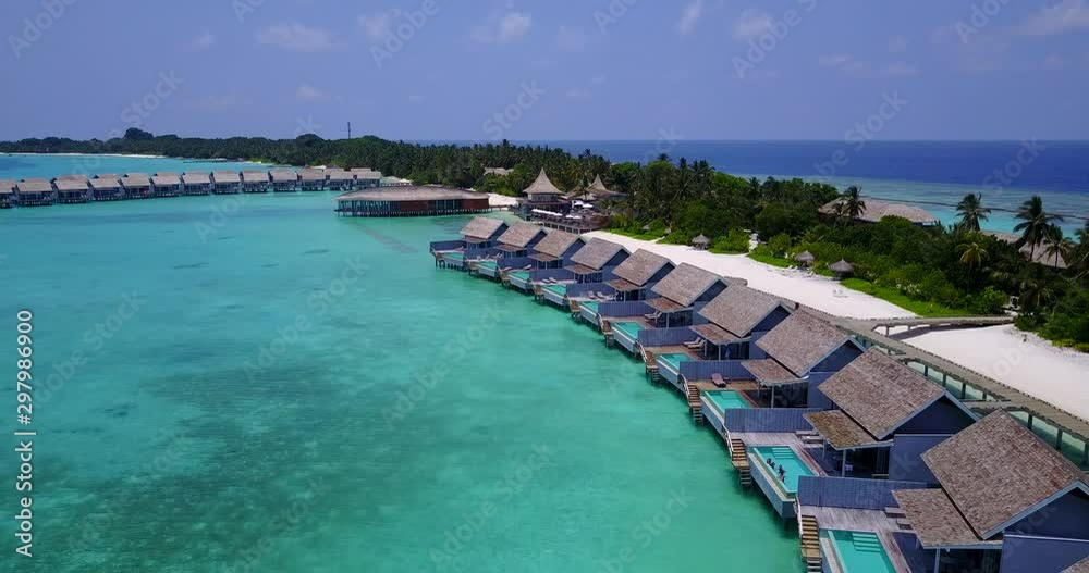 Row of beautiful luxury bungalows of tropical resort over shallow turquoise water near tropical beach in The Maldives Row of beautiful luxury bungalows of tropical resort over shallow turquoise water near tropical beach in The Maldives
