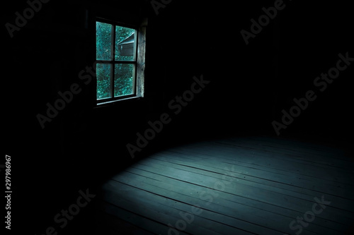 Abstract horror background for halloween. Gloomy scary terrible window with ghostly light and shadows in a dark black room in the attic, corridor or basement in an abandoned house in the forest