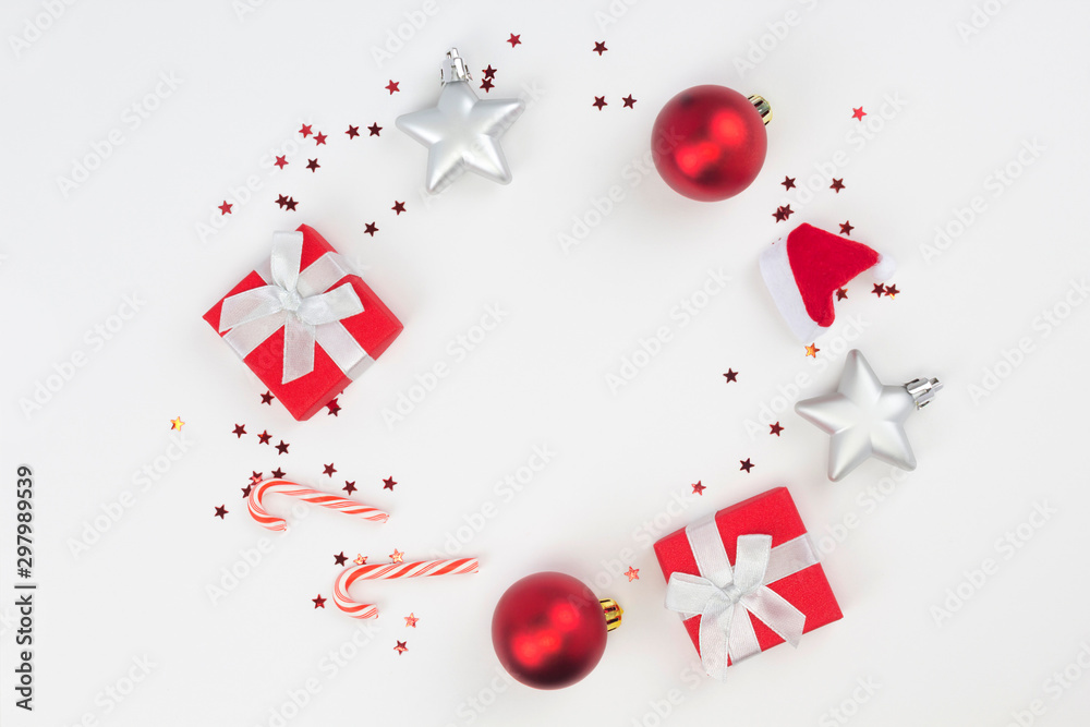 Round frame from red Christmas gifts, balls, star confetti, candy canes on white background. Congratulation, Happy New Year concept. Top view, flat lay, copy space Round frame from red Christmas gifts, balls, star confetti, candy canes on white background. Congratulation, Happy New Year concept. Top view, flat lay, copy space