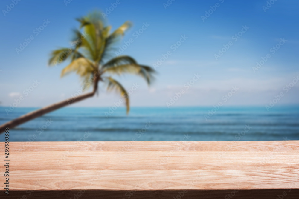 Empty wooden table on the background of tropical beach with palm.