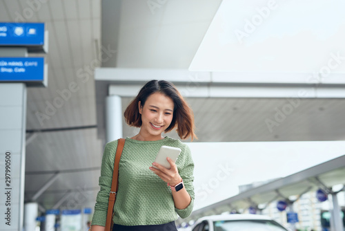 Asian woman is checking her smartphone as she waits in airport in Asia.