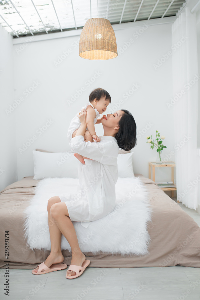 Mom playing with her little girl on bed 