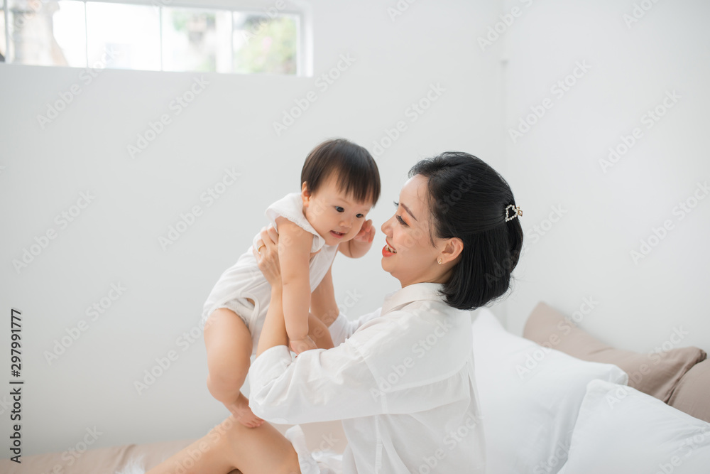 Young mother playing with her baby in bedroom at home Young mother playing with her baby in bedroom at home