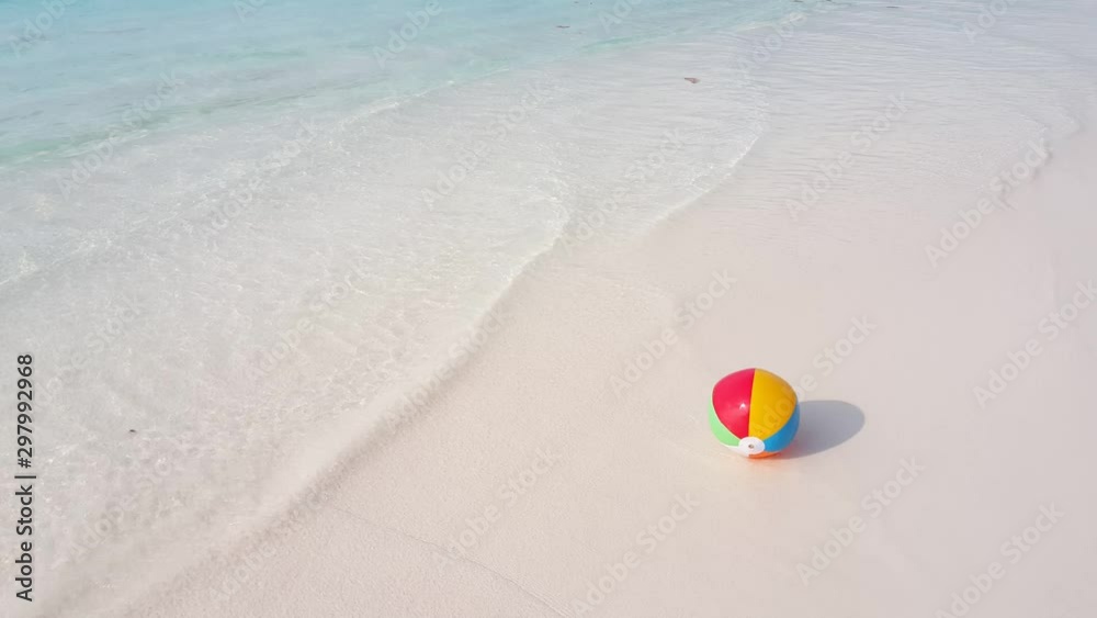 colorful beachball on the sandy beach, rolling around when waves pull it over, Family summer vacation concept colorful beachball on the sandy beach, rolling around when waves pull it over, Family summer vacation concept