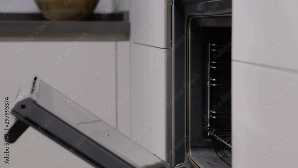 Close up multiple shots of a man putting a red pan inside the oven and turning it on