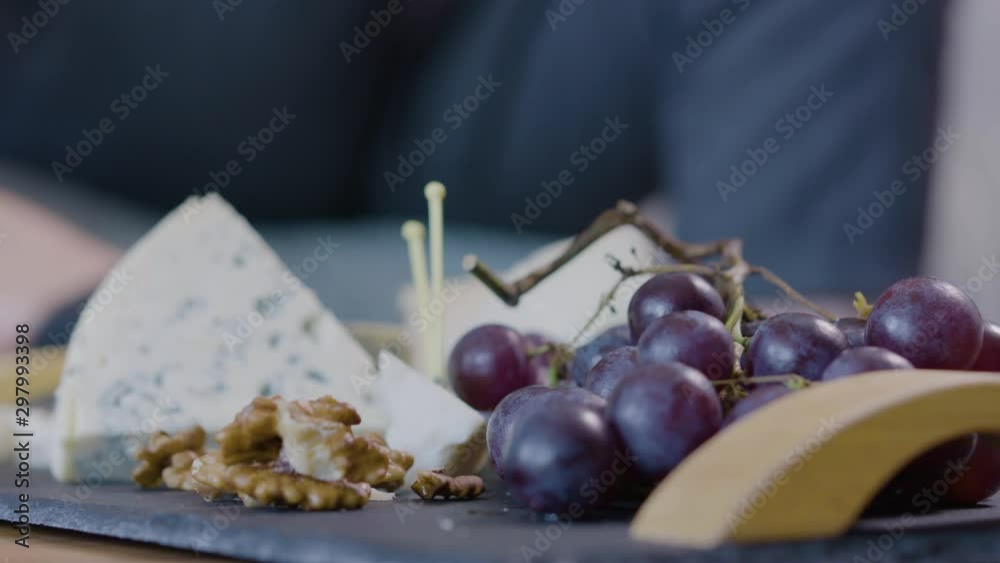 Close up of snacking from a cheese platter with grapes, nuts and a glass of wine Close up of snacking from a cheese platter with grapes, nuts and a glass of wine