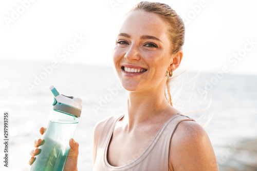 Fototapeta Naklejka Na Ścianę i Meble -  Smiling young sports woman outdoors on beach