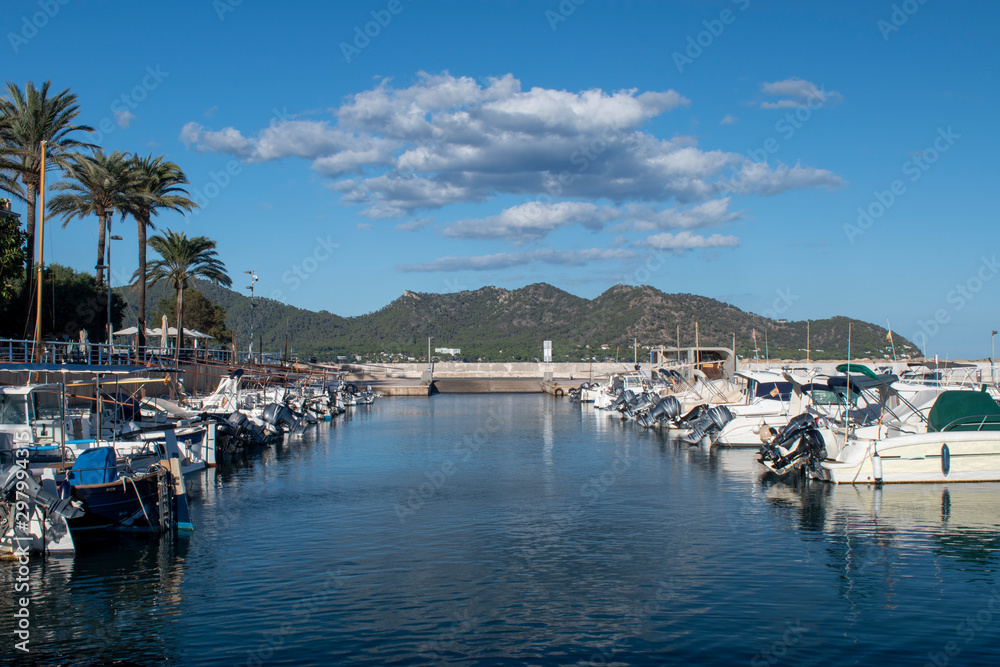 Boats moored in the busy little marina of  Cala Bona in Majorca on a very calm and warm day with the water flat on a beautiful day at this popular holiday destination.